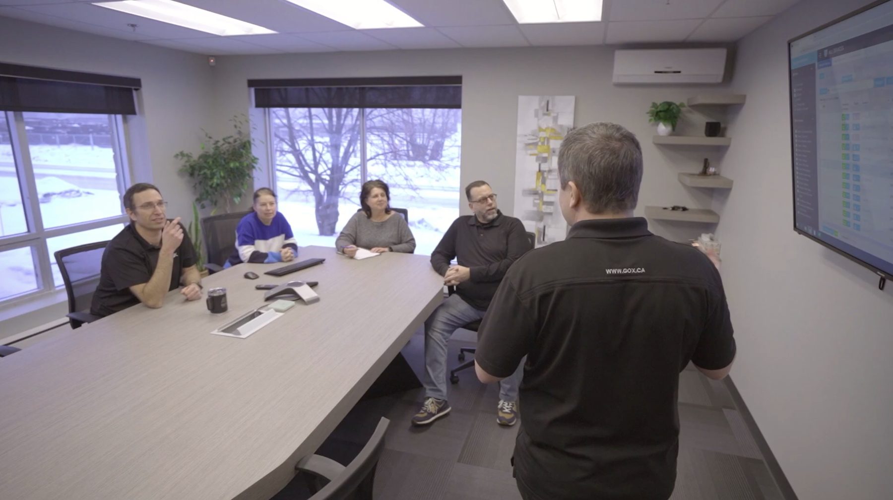 A GOX briefing around the table, snow outside, a live board on the wall.